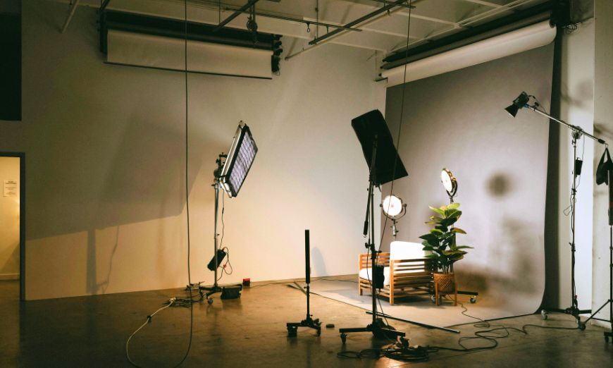 Photo studio with lights, a white backdrop, and an armchair set up for a shoot