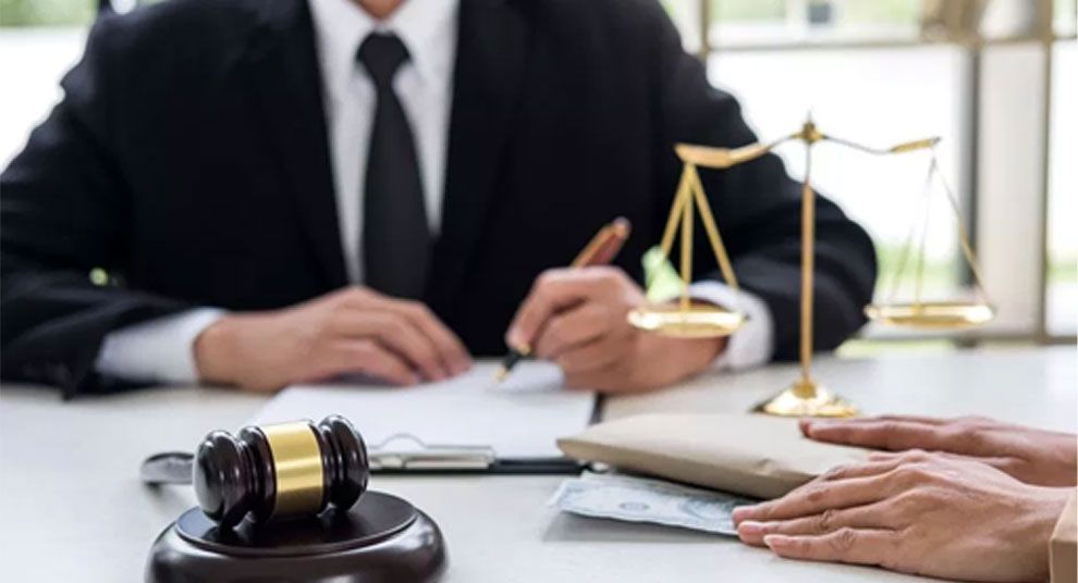 Lawyer signing a document next to a judge gavel and the scales of justice