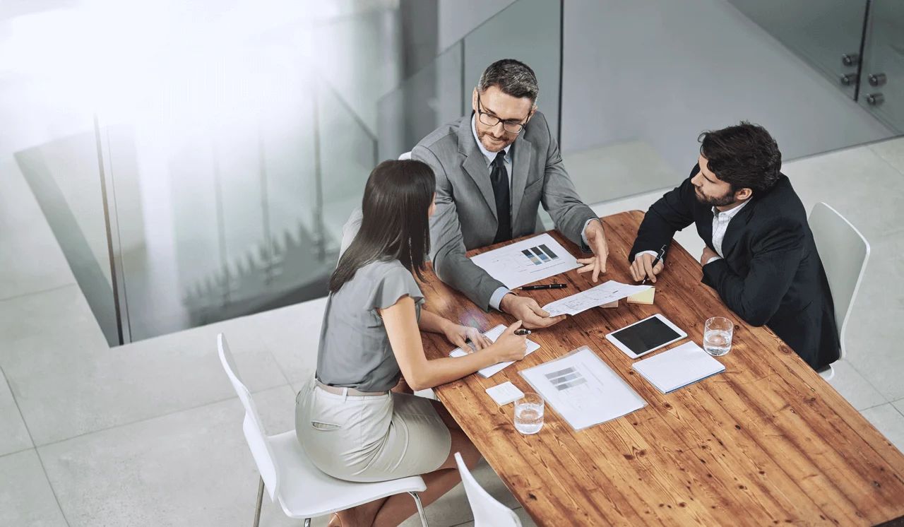 Three professionals reviewing documents in a meeting